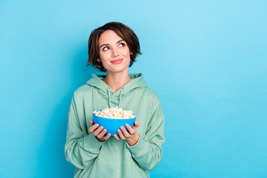 Photo of thoughtful cute lady dressed green pullover holding pop corn plate empty space isolated blue color background