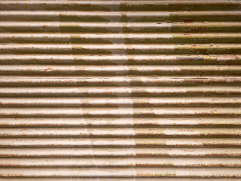 Abstract background texture of a worn, tattered corrugated metal wall with parallel grooves.