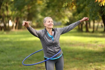 Senior woman exercising with hula hoop outdoors © New Africa