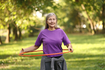 Senior woman exercising with hula hoop outdoors © New Africa