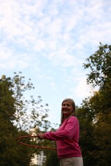 Senior woman exercising with hula hoop outdoors, low angle view © New Africa