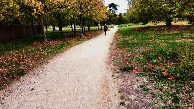 PARIS, FRANCE - OCTOBER 19, 2026: A person jogging through scenic nature in the morning and breathing fresh air in a peaceful park in Paris, France.