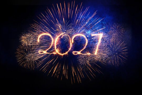 Happy New Year 2027 written with glowing sparkler light against bright fireworks in dark night sky, symbolizing celebration, holiday event, party background, hope, future, and joyful festival.