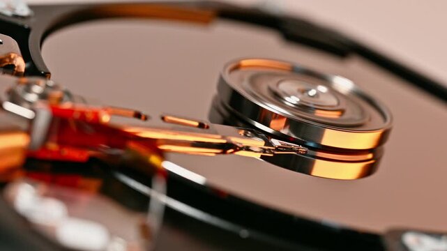Extreme close up of the internal mechanism of a hard disk drive showcasing shiny metallic components. Precision engineering with smooth motion in data storage technology.