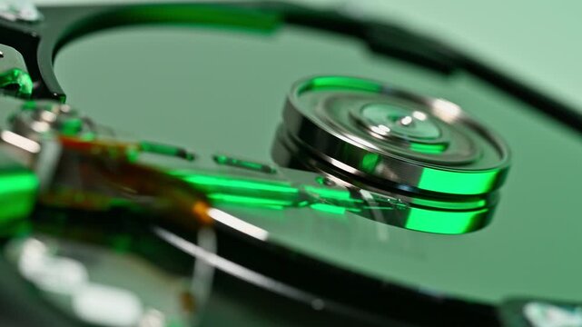 Extreme close up of a storage drive showing reflective green circular disks and mechanical parts. Intricate details of technology and data storage system.