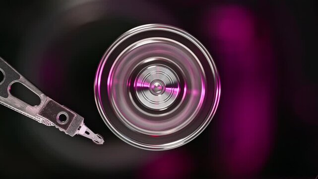 Extreme close-up of a hard drive platter rotating in dark purple lighting. High speed mechanical storage device, computer hardware components, data centers.