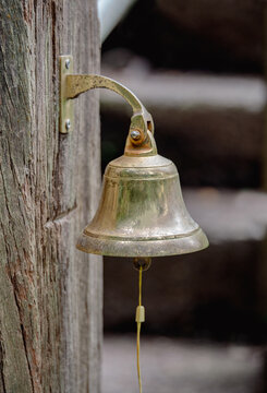A vintage brass bell mounted on a weathered wooden post for a rustic home entrance decoration