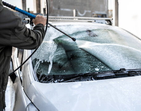 Washing white car windshield with high pressure water spray