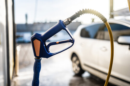 Blue car wash spray gun held near vehicle outdoors