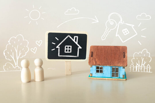 Dream Home and First Time Home Buyers Concept with Wooden Couple House Model and Key Illustration.