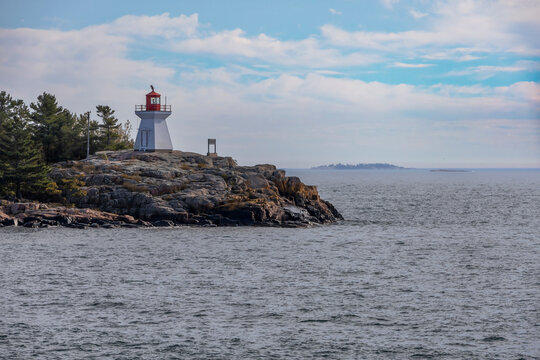 A picturesque lighthouse on rocky shores of Georgian Bay, Killarney, Ontario, under a wide sky.