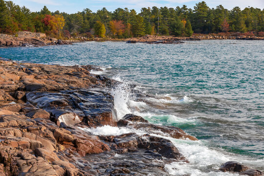 Rugged rocks meet Georgian Bay's waves, surrounded by Killarney's vibrant autumn forest.