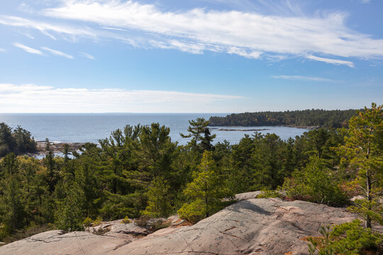 Breathtaking view of Georgian Bay from Killarney's Lighthouse Trail, featuring lush forests and rugged shoreline under a clear blue sky.