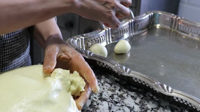 Shaping trid dough into small oiled balls on a silver tray