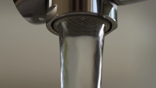 Clean water pouring from modern chrome faucet in close up view