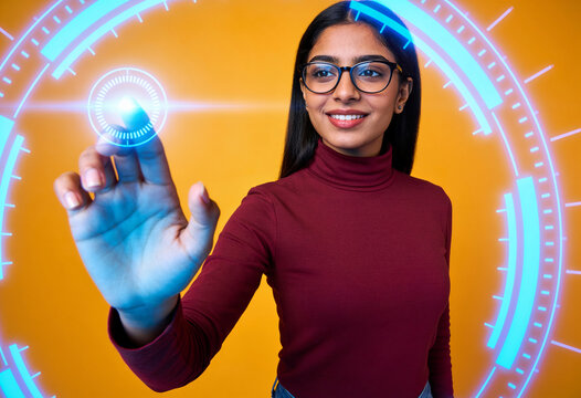 Indian woman wearing glasses touching futuristic digital interface circular hud on bright orange background studio