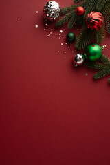 Plakat Festive decoration surrounds ornaments and pine branches on a vertical maroon red background