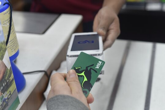 Man making a contactless payment at local shop.