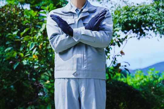 自然の背景でNGポーズする作業服の男性