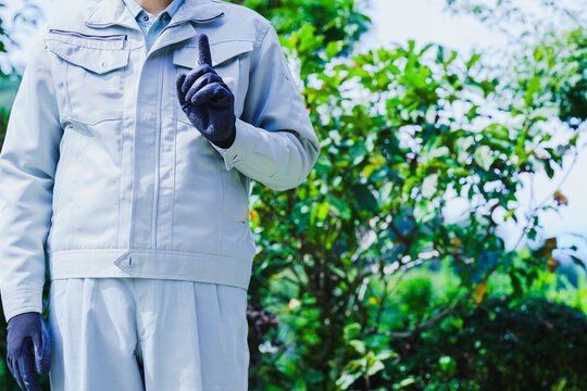 自然の背景で人差し指を立てる作業服の男性