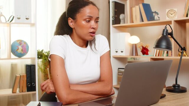 African American young woman on home table searches jobs online sends CV with laptop awaiting employer reply. Black girl checks application feeling calm focused hopeful and patient during job search.