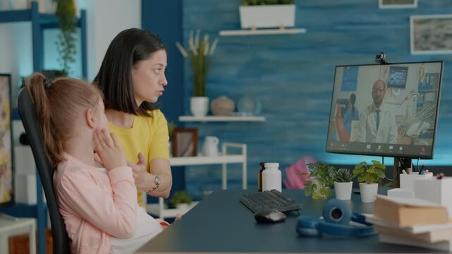 Dentist, toothache and telemedicine with mother supporting daughter who touches a sore jaw during video call, for remote oral care, dental advice, pain consultation and family healthcare.