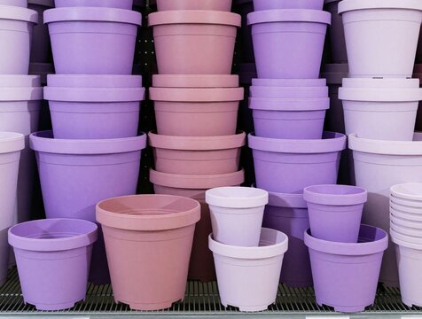 Purple, pink plastic flower pots stacked on retail shelves. Various sizes of garden containers displayed in florist shop garden center. Colorful empty planters for plants, flowers available for sale