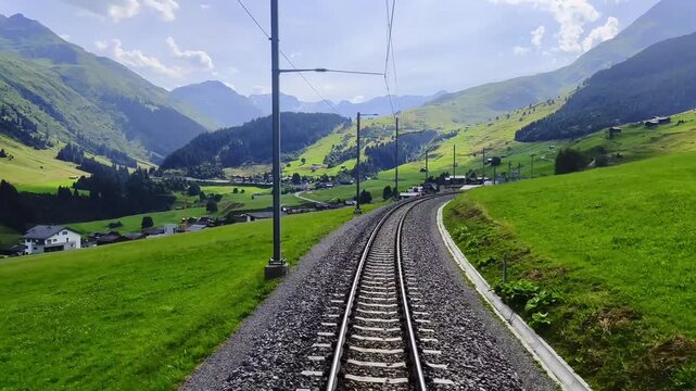 Rear View From Glacier Express on Railroad Tracks and Mountainscape and Valley in a Sunny Summer Day in Sedrun, Surselva, Oberalp, Grisons, Switzerland