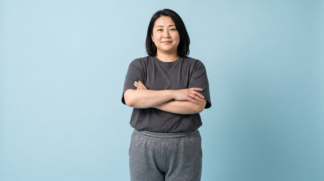 白背景で腕を組んで自信に満ちた表情の太り気味のふくよかな体型の40代日本人女性：筋トレ・ボディメイクの成果のイメージ