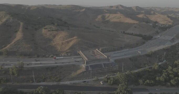 Aerial Pan of Highway Traffic Passing a Wildlife Overpass in Dry Hills