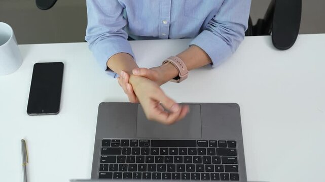 Office worker pauses typing to stretch her wrist