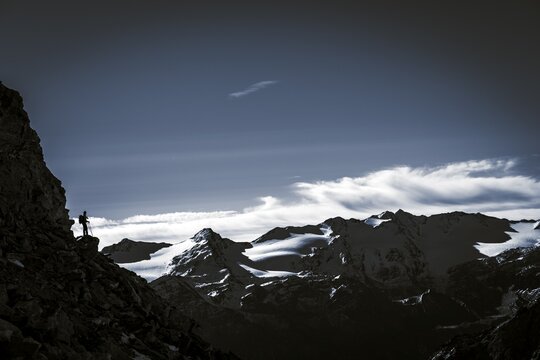 Climber on rocky outcrop with South Tyrolean mountains at blue hour, Martell Valley, Naturno, South Tyrol, Italy