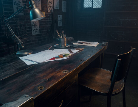 Dimly Lit Vintage Design Workshop with Blueprints, Color Swatches, and an Adjustable Desk Lamp