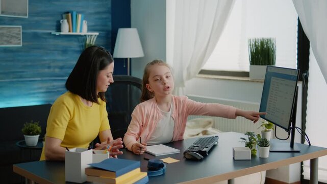 Homework, computer and discussion as a child points to information on the monitor while studying with a parent at home, for remote learning, school tasks, guidance and communication.