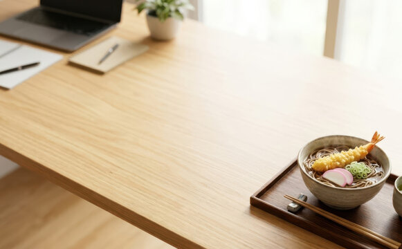 Wooden office desk with a bowl of Japanese tempura soba noodles for lunch break
