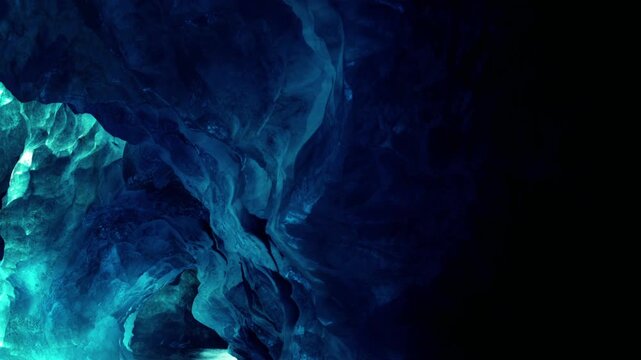 Massive blocks of translucent blue ice create a glowing natural tunnel within a dark mountain cavern environment where light reflects softly off the textured frozen walls during a cold winter evening