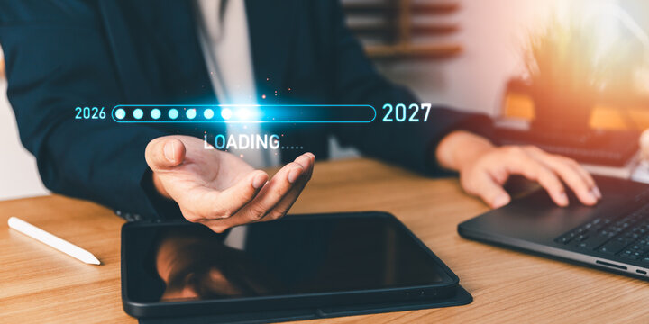 Businessperson holding a digital loading progress bar transitioning from 2026 to 2027, planning future business strategy, annual corporate growth, and welcoming the new year with modern technology