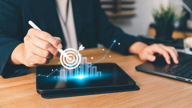 Businessperson touching digital target icon and financial growth chart on tablet screen, planning business strategy, setting goals, and analyzing company performance success with modern technology