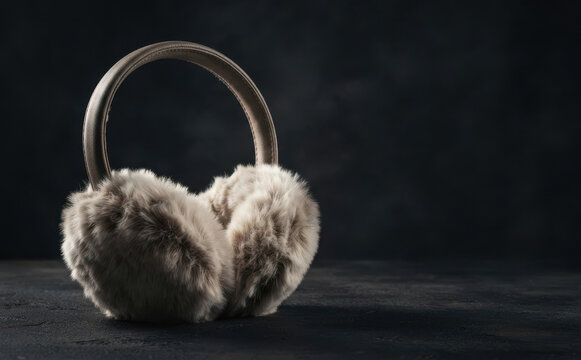 Fluffy winter earmuffs on dark background, cozy apparel accessory for cold weather season