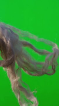 Natural flax linen strands swirling and dancing in a gentle breeze over a solid green backdrop suitable for video editing