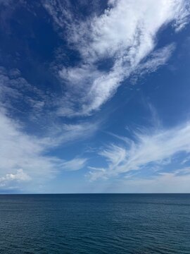 Calm blue ocean and sky covered with beautiful clouds vertical 