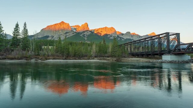 Canadian Rockies Mount Rundle mountain and Canmore Engine Bridge over Bow River during autumn sunrise time-lapse. Canmore, Alberta, Canada.