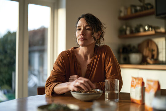 A contemplative woman enjoys her breakfast, sitting at a beautifully arranged table filled with healthy choices, highlighting a moment of mindfulness and self-care in her daily life.