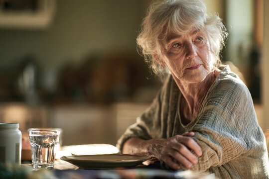 This serene image displays an elderly woman lost in thought at a kitchen table, highlighting the beauty of introspection during quiet moments of life.