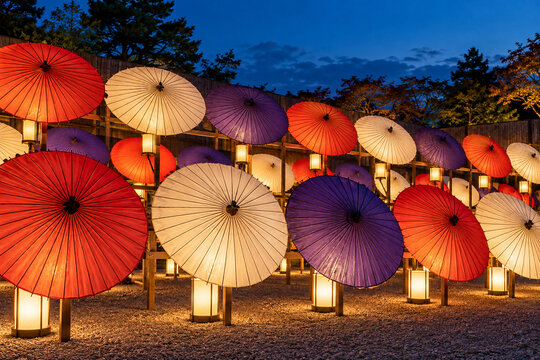 Paper umbrellas lit by lanterns at a garden display at blue hour