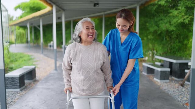 Warm smiles fill this gentle care moment. Young caregiver walks beside elder with quiet support. Elder laughs, pointing joyfully at something distant