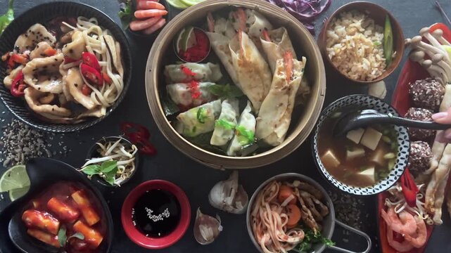 Assorted Chinese dishes served in bowls on a dark background. Top view.