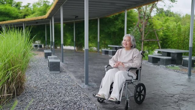 Senior woman smiles peacefully in wheelchair. She sits under covered outdoor seating area. Natural light enhances calm, serene atmosphere