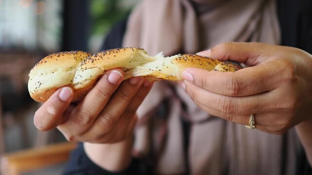 A person breaking a row of seeded bread rolls 