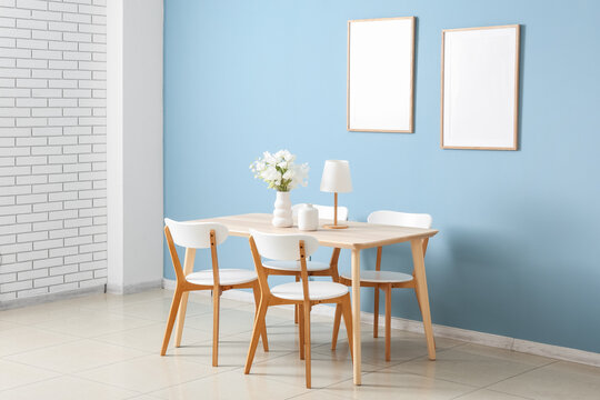 Interior design and home staging, dining room with wooden table and empty picture frames on blue wall for modern apartment renovation and lifestyle